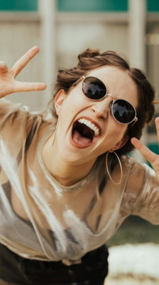 selective focus photography of jolly woman using peace hand gesture