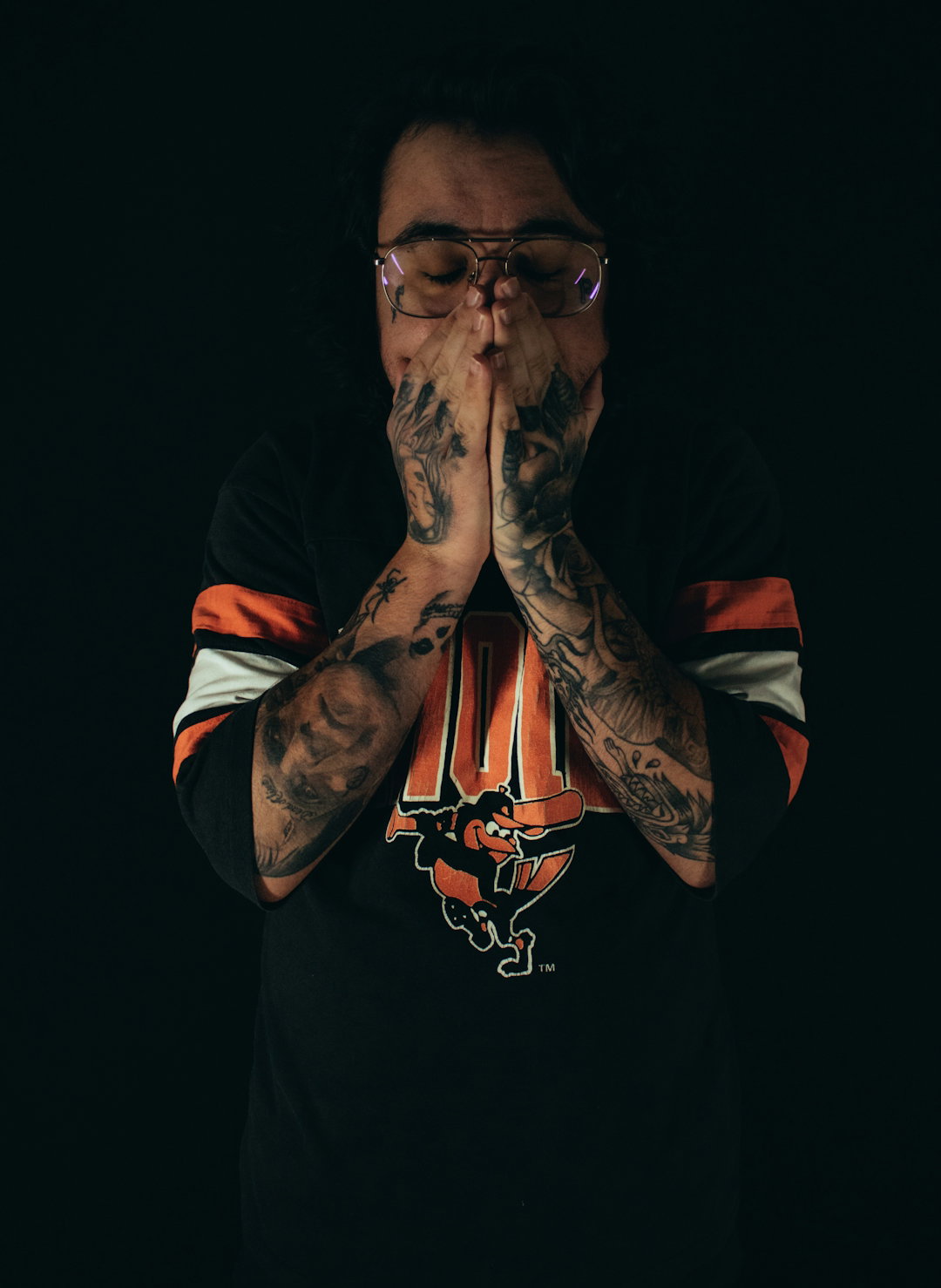 a man with tattoos and glasses covering his face